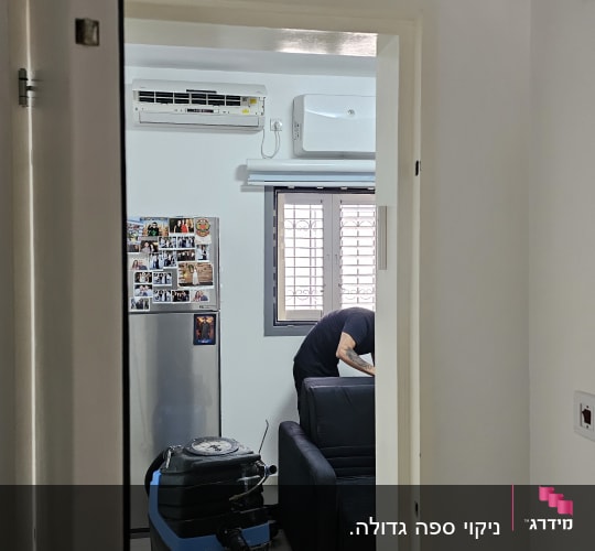 מכונת ניקוי ספות ליד ספה שחורה בחדר